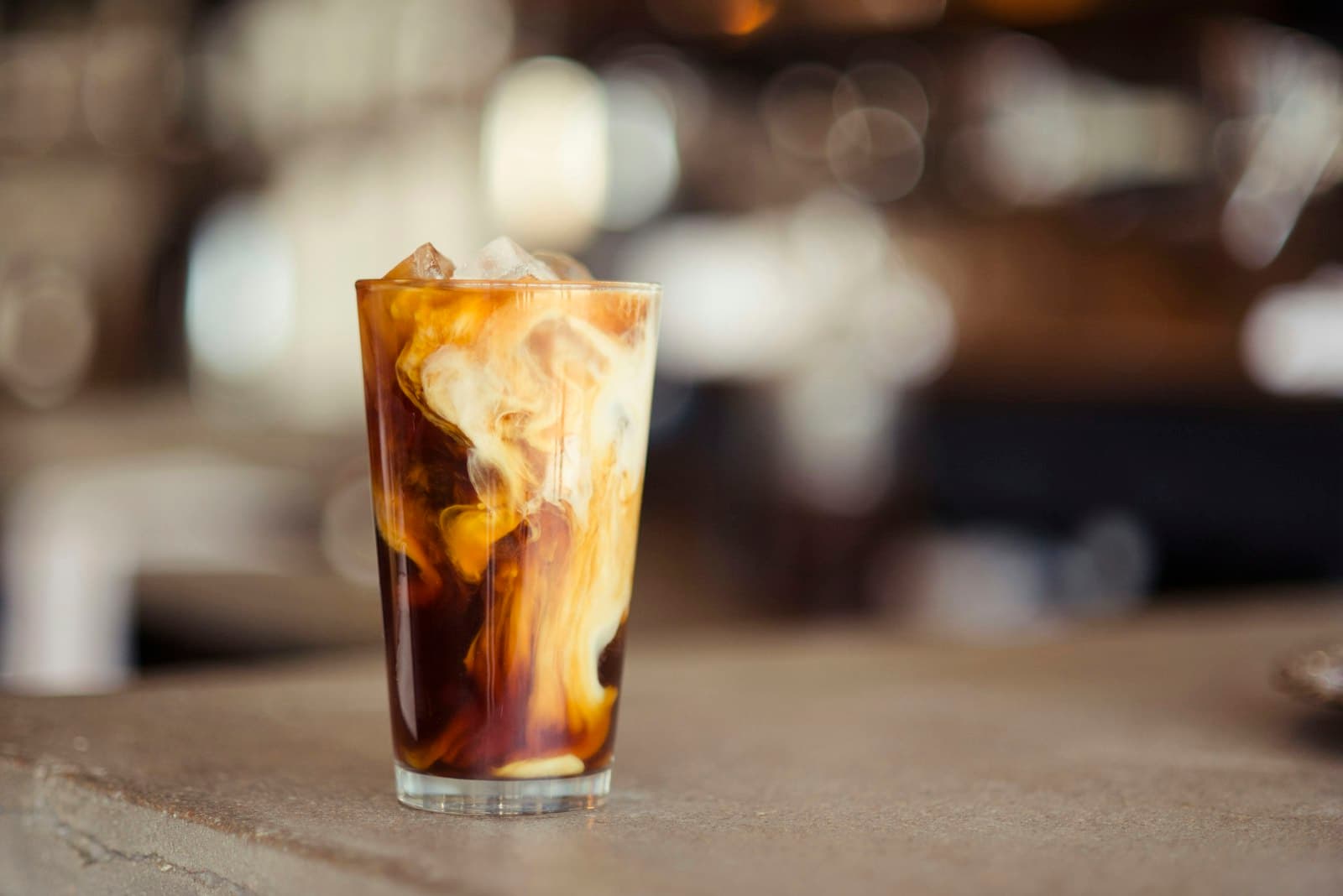 Iced coffee with milk swirling through it